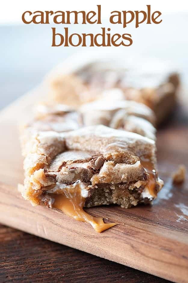 A blondie square with caramel coming out of it on a cutting board.