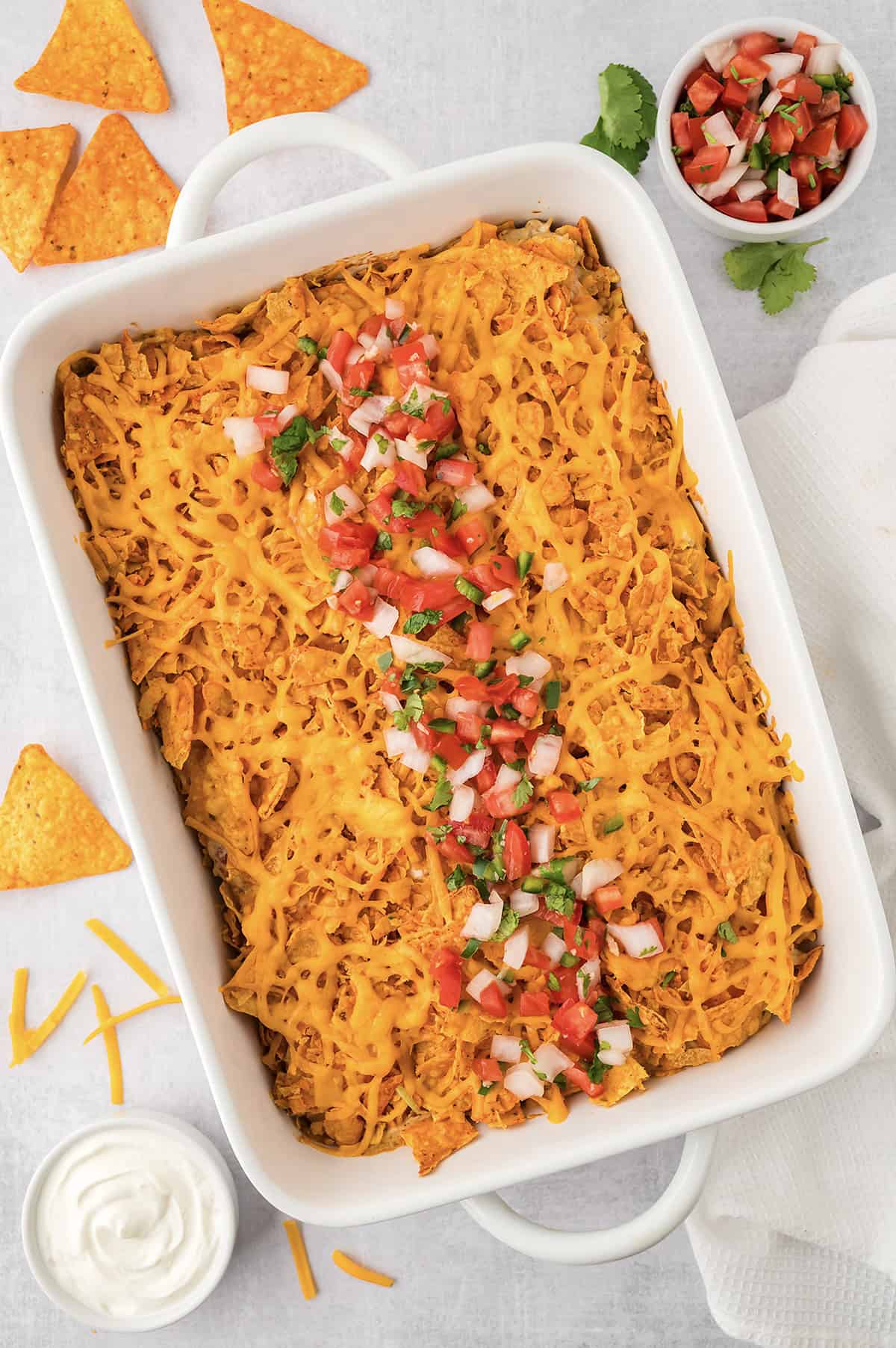Chicken Doritos casserole in white baking dish, topped with pico de gallo.