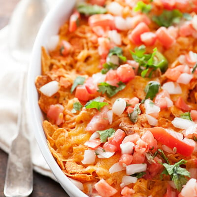 A close up of Dorito pieces, diced chicken and diced onions in a white baking dish.