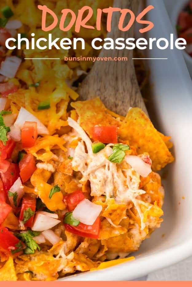 Wooden spoon in dish full of chicken and dorito casserole.