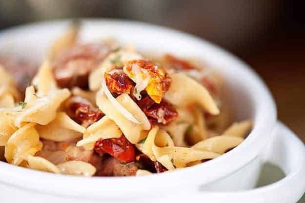 A close up of chicken and noodles in a white bowl.