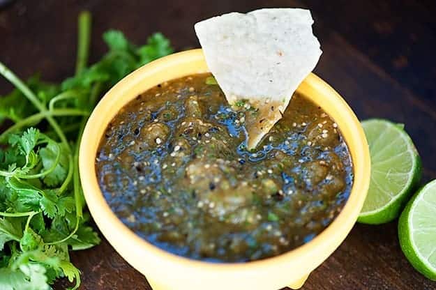 A tortilla chip dipped into a bowl of salsa verde.