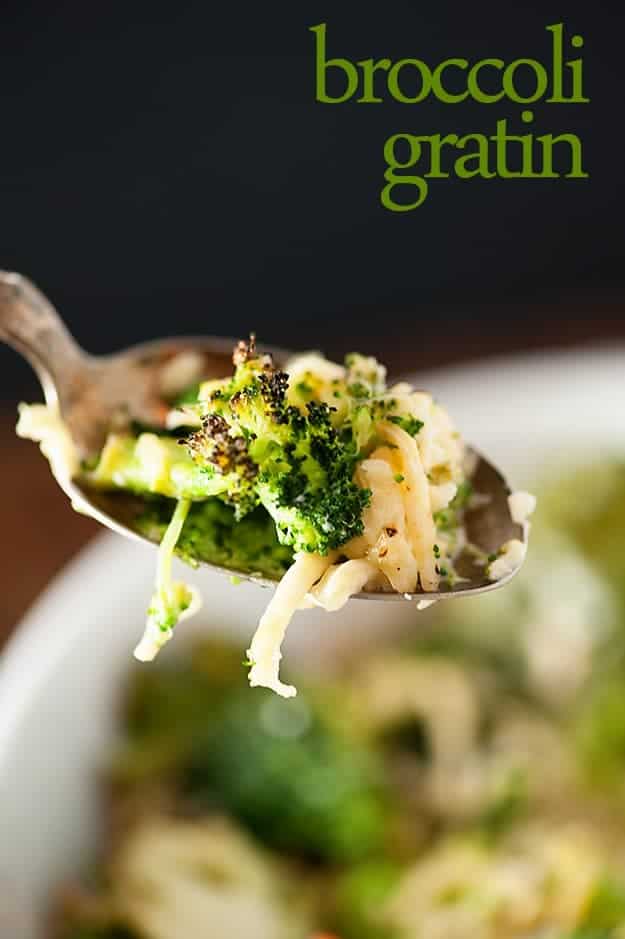 A spoon of broccoli above a bowl of cheesy broccoli.