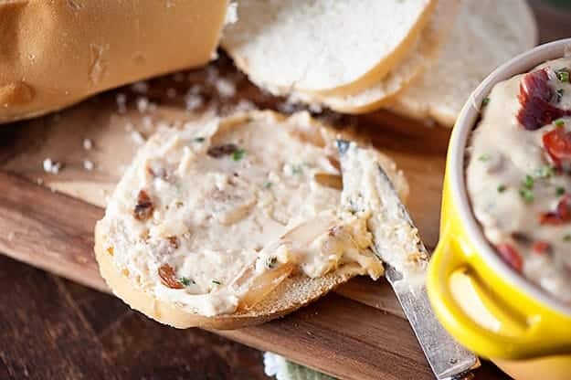 A knife spreading onion dip on a slice of bread.