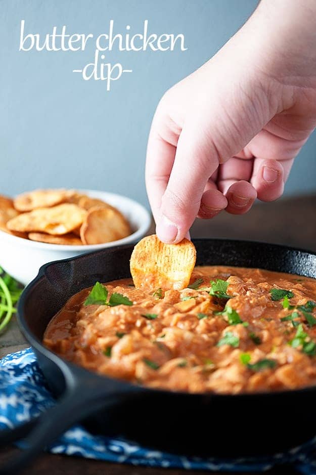 A person dipping a chip into a skillet of chicken dip.