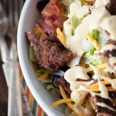 A bacon cheeseburger salad in a white bowl.