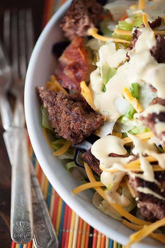 A bacon cheeseburger salad in a white bowl.