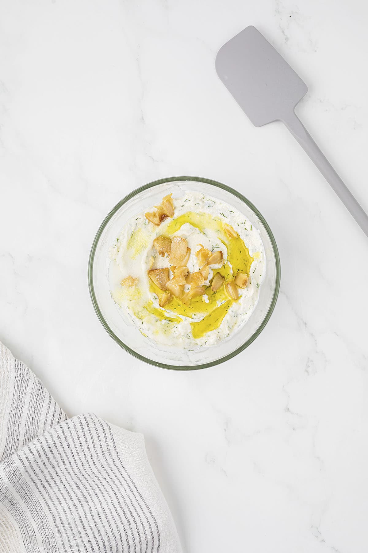 Roasted garlic and olive oil in bowl full of ricotta.