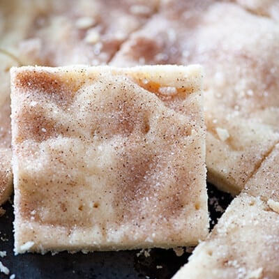 A close up of a square of shortbread cut out of a baking sheet full of shortbread.