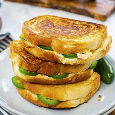 Stack of jalapeno popper grilled cheese sandwiches on plate.