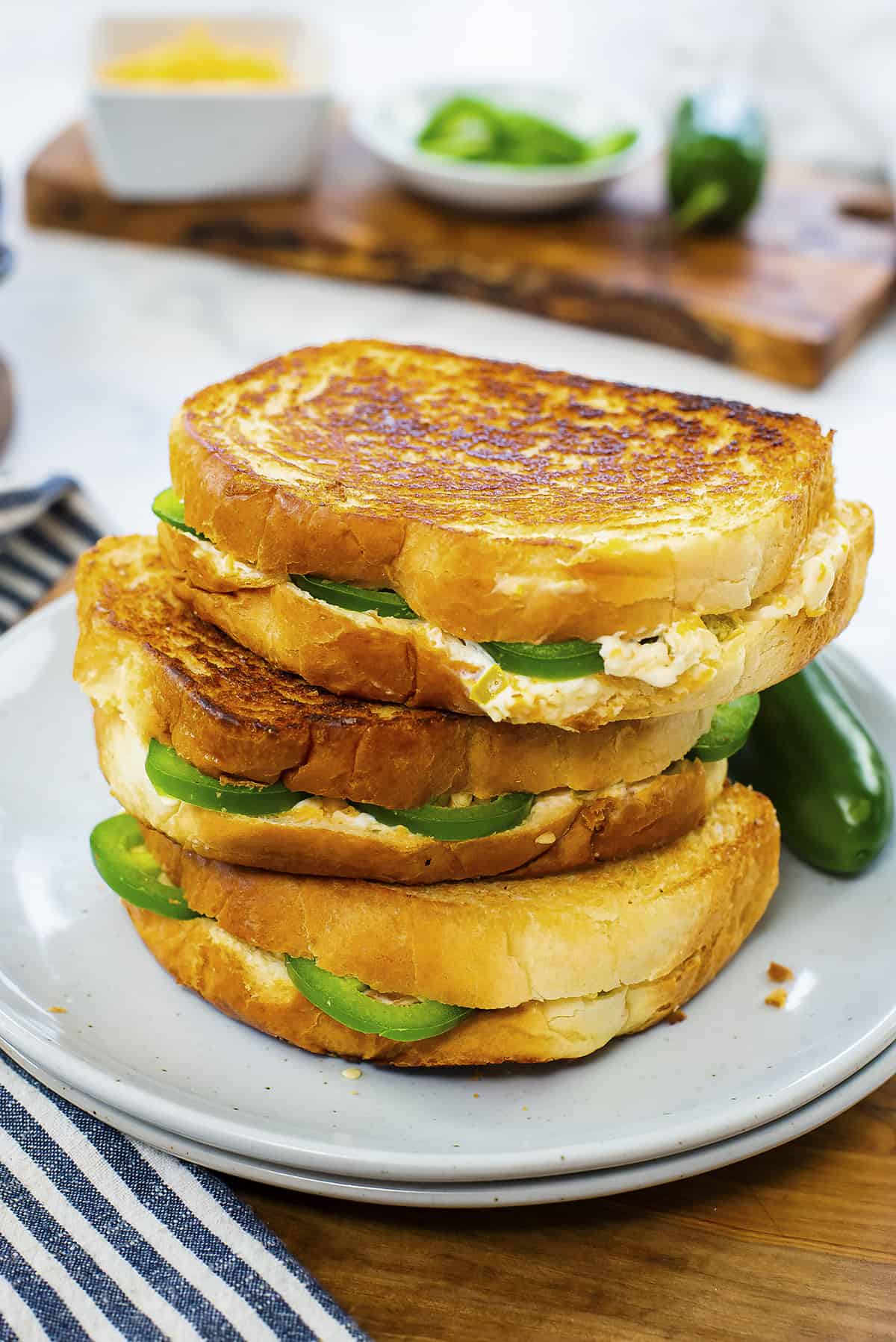 Stack of jalapeno popper grilled cheese sandwiches on plate.