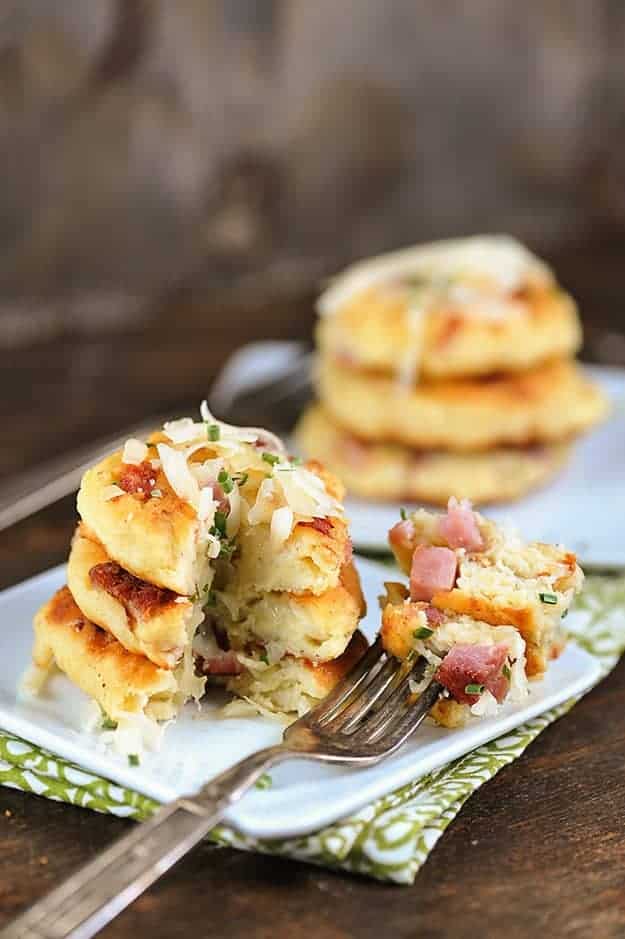 A bite of cheesy potato pancakes on a square plate.