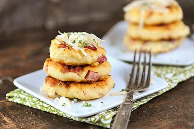 Three stacked up mini potato pancakes on a square plate.