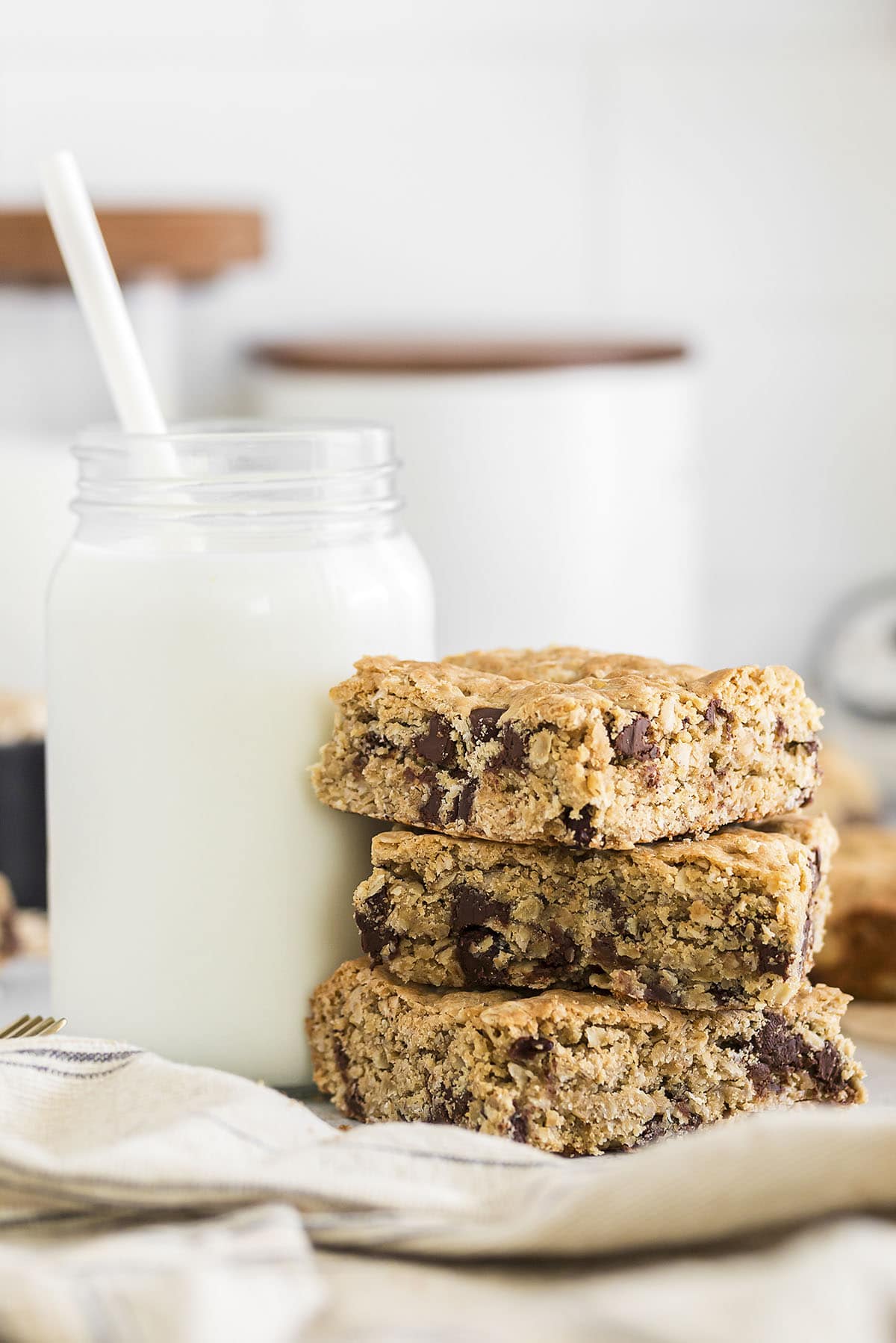 Stack of oatmeal cookie bars next to glass of milk.