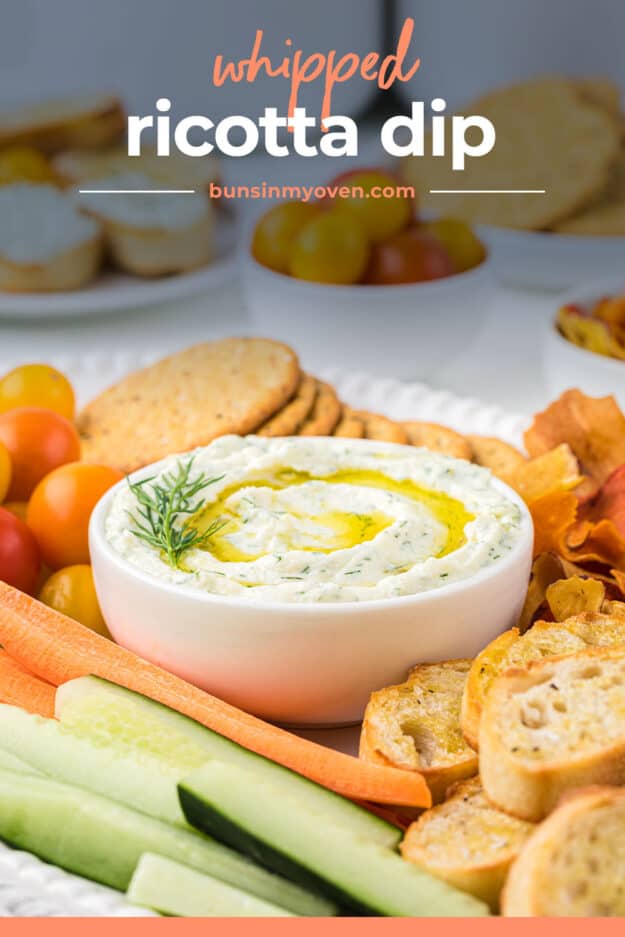 Small bowl full of ricotta dip surrounded by fresh vegetables and crackers.
