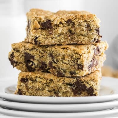 Stack of oatmeal cookie bars on stack of white plates.