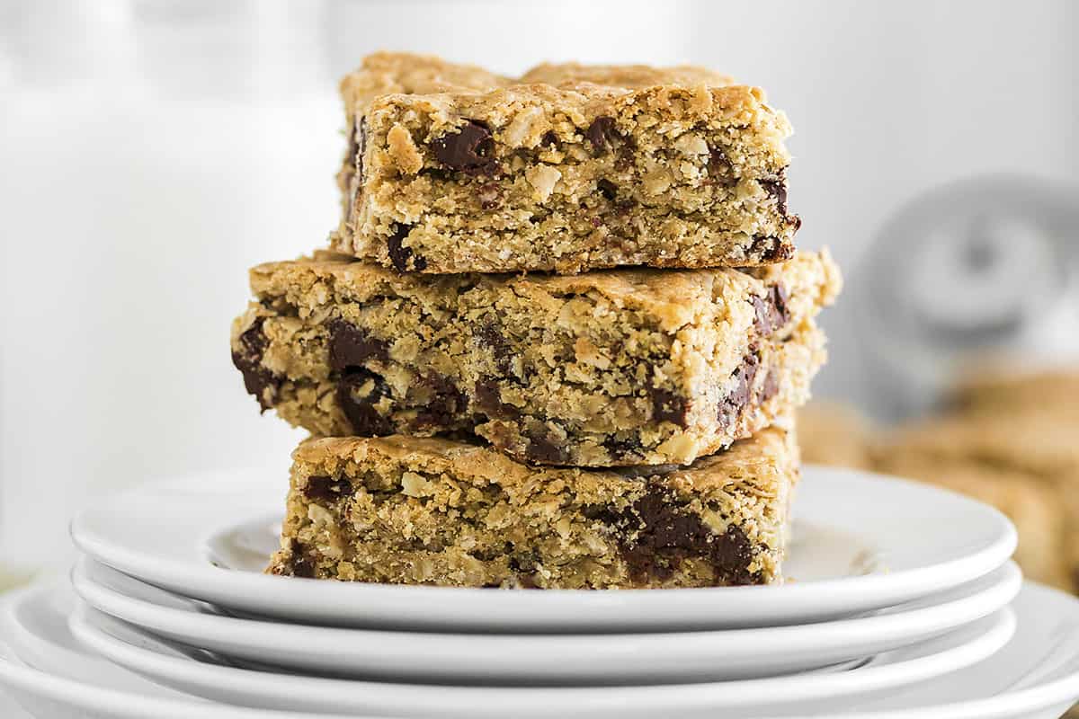 Stack of oatmeal cookie bars on stack of white plates.