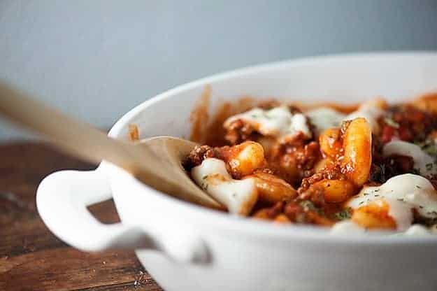 A white bowl of gnocchi on a wooden table.