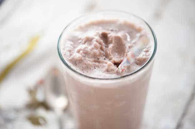 A protein shake in a clear glass with a straw in it.
