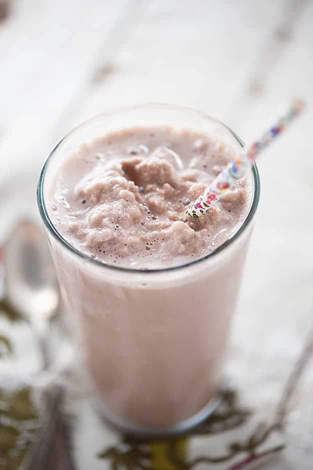 A protein shake in a clear glass with a decorative straw.