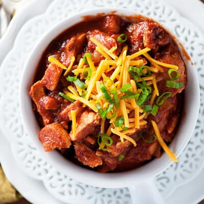 Overhead view of chili and shredded cheese in a white bowl.