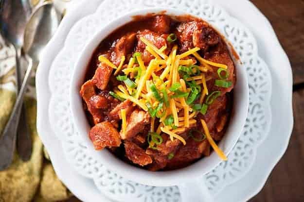 Overhead view of chili and shredded cheese in a white bowl.