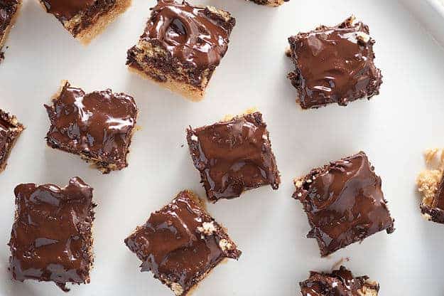 Overhead view of many squares of chocolate ritz bars on a white cutting board.