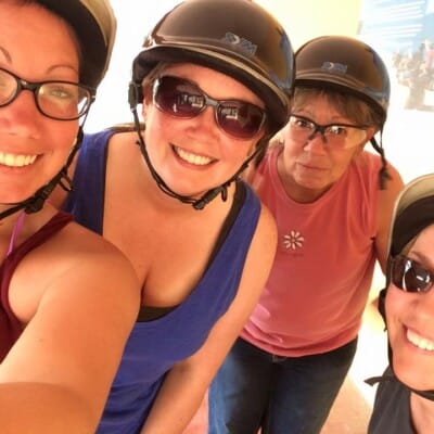 A group of women in motorcycle helmets posing for the camera.
