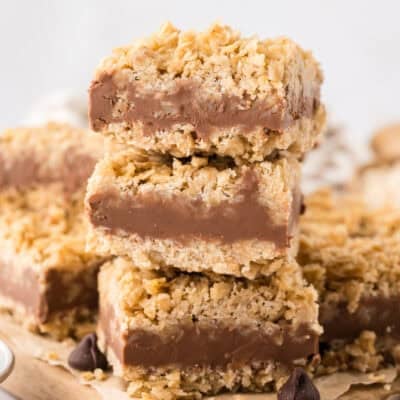 Stack of no bake chocolate oat bars on wooden cutting board.
