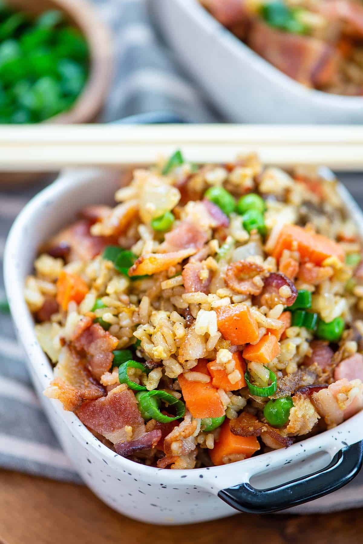bacon fried rice in small white dish with chopsticks.