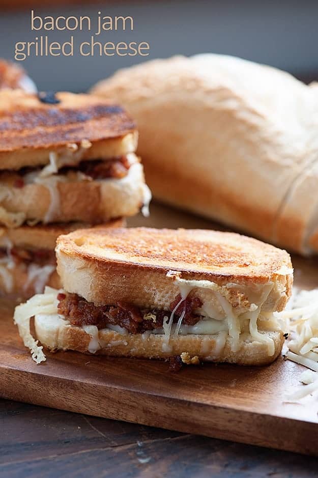 A sandwich sitting on top of a wooden table with melted cheese going down the side.