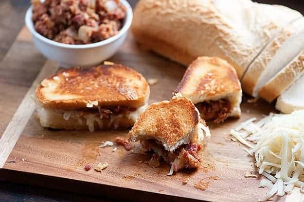 A bacon jam grilled cheese cut into pieces on a wooden cutting board.