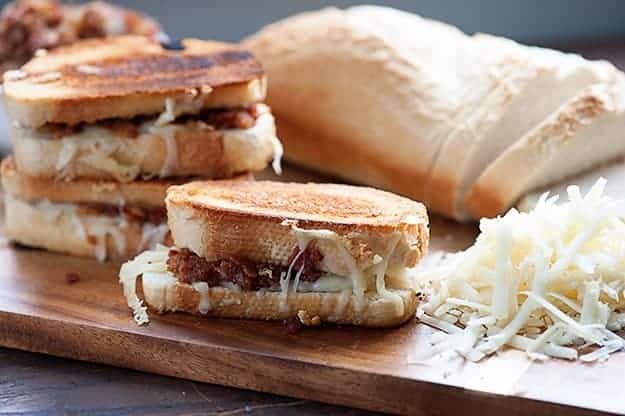 A few grilled cheese sandwiches on a wooden cutting board.