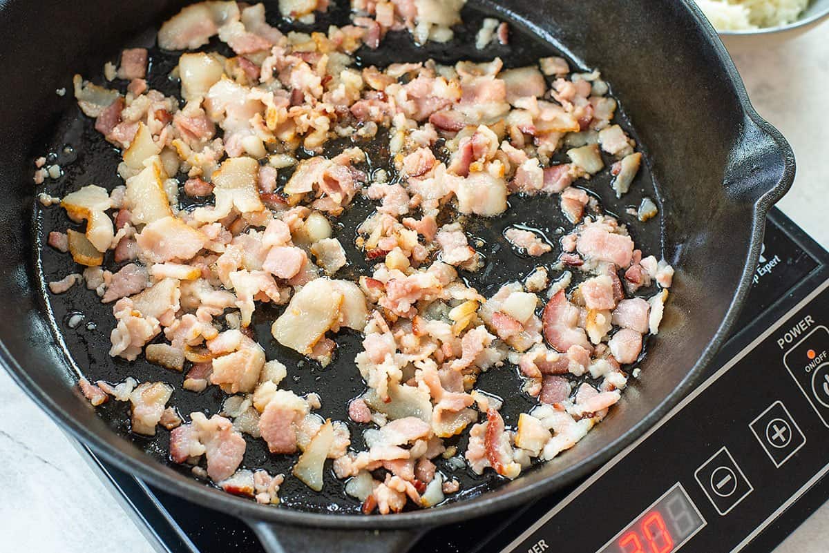 bacon being cooked in skillet.