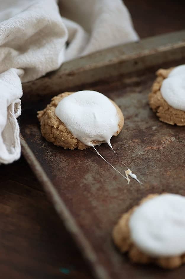 A close up of some marshmallow-topped cookies on a baking sheet.