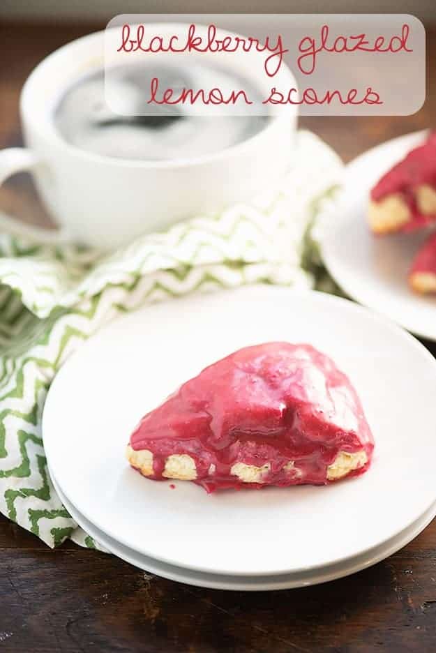A scone covered in a blackberry glaze on a white plate.