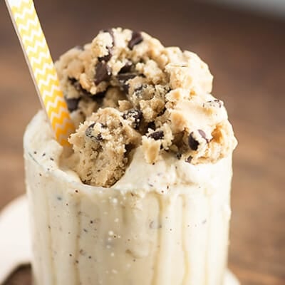 A close up of a scoop of cookie dough on top of ice cream in a glass.