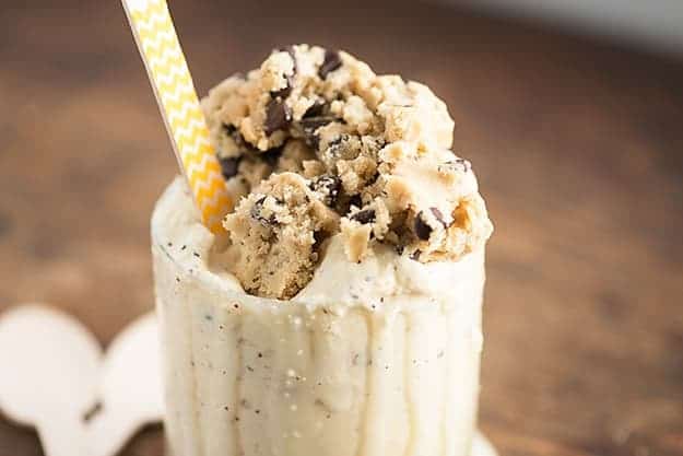 A close up of a scoop of cookie dough on top of ice cream in a glass.