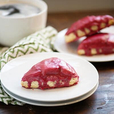 A couple of white plates with blackberry scones on top.