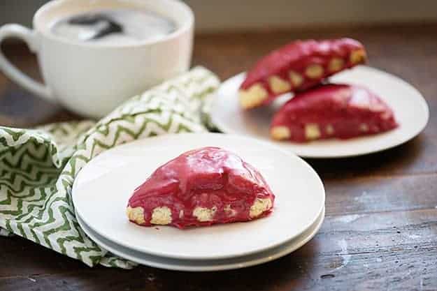 A couple of white plates with blackberry scones on top.