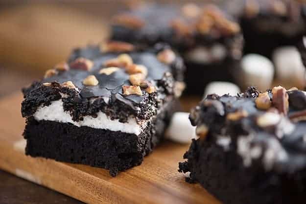 A close up of several brownies on a wooden cutting board.