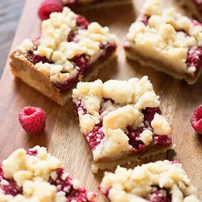 A few small squares of raspberry crumb bars on a cutting board.