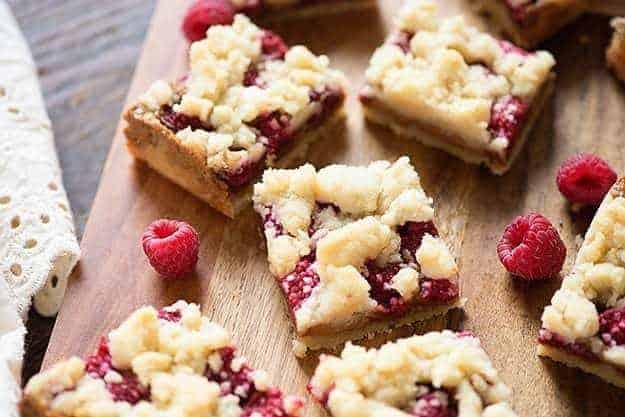 A few small squares of raspberry crumb bars on a cutting board.