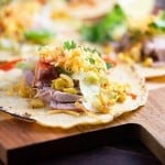 A close up of an open pork taco on a wooden cutting board.