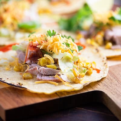 A close up of an open pork taco on a wooden cutting board.