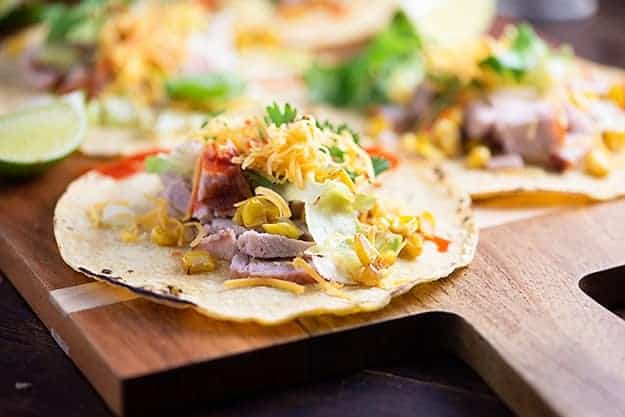 A close up of an open pork taco on a wooden cutting board.