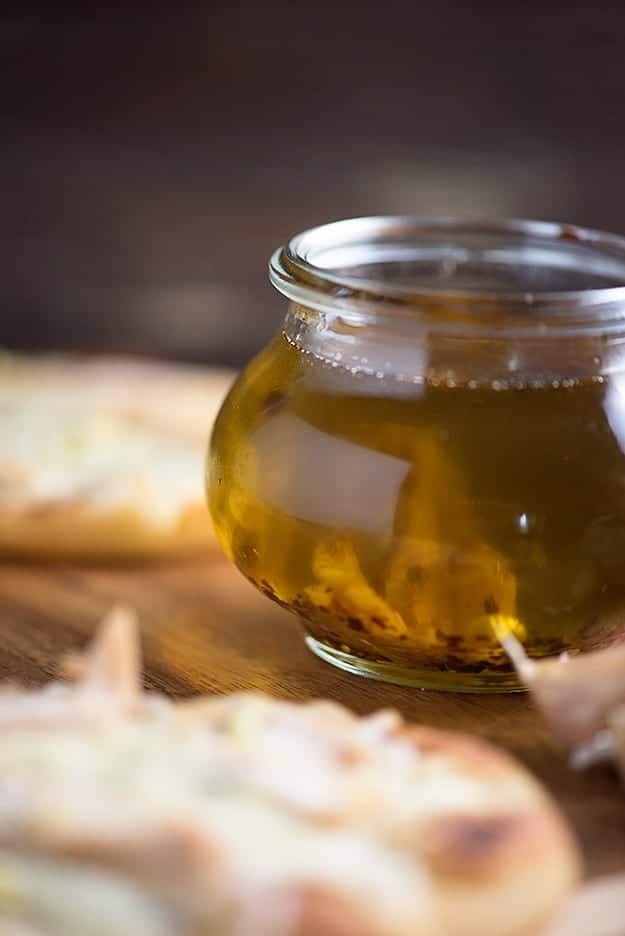 A close up of a glass jar of garlic oil on a cutting board.