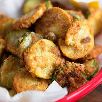 Fried zucchini slices stacked on top of each other in a red appetizer tray.