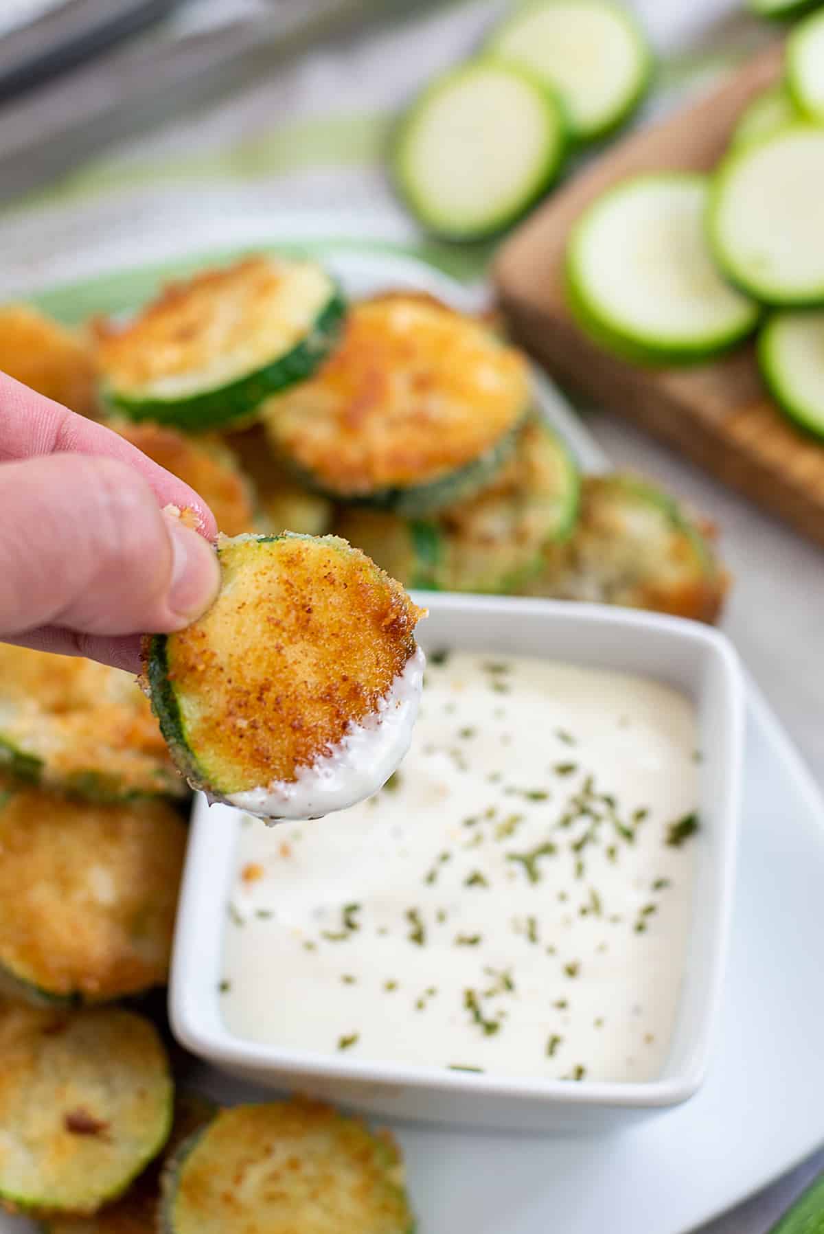 fried zucchini being dipped in ranch.