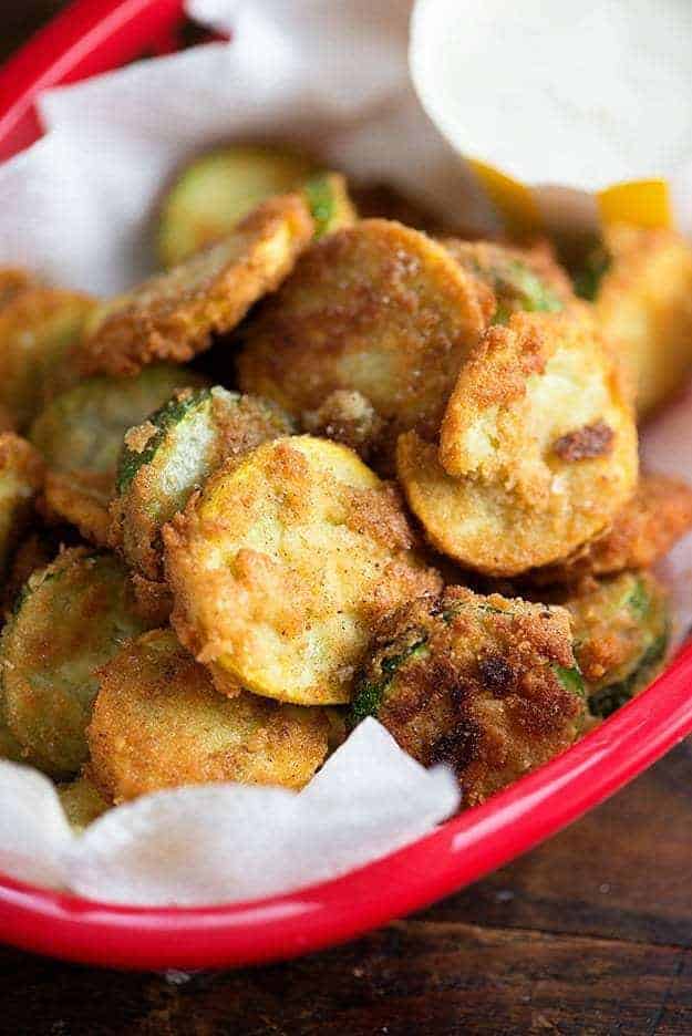 Fried zucchini slices stacked on top of each other in a red appetizer tray.